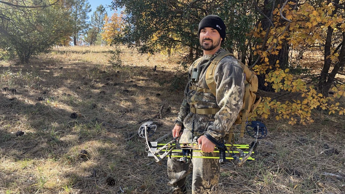 Trent in camouflage with a compound bow in the mountains