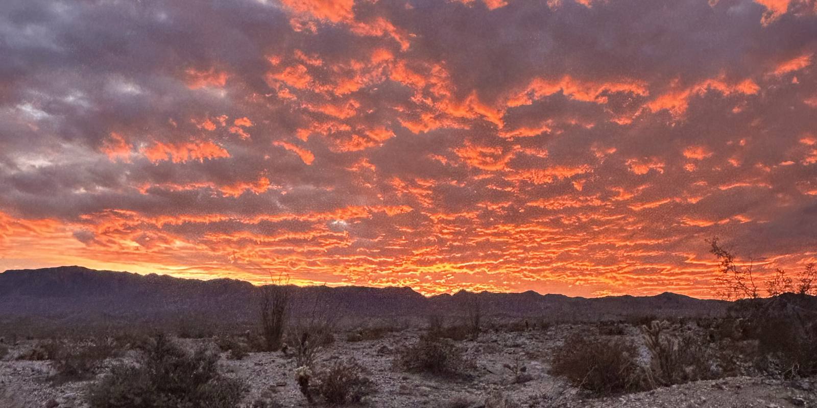 Orange sunset clouds over the desert and distant mountains at Ocotillo